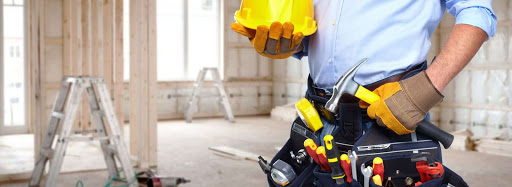 Construction worker holding helmet with hammer and standing with belt fitted with tools